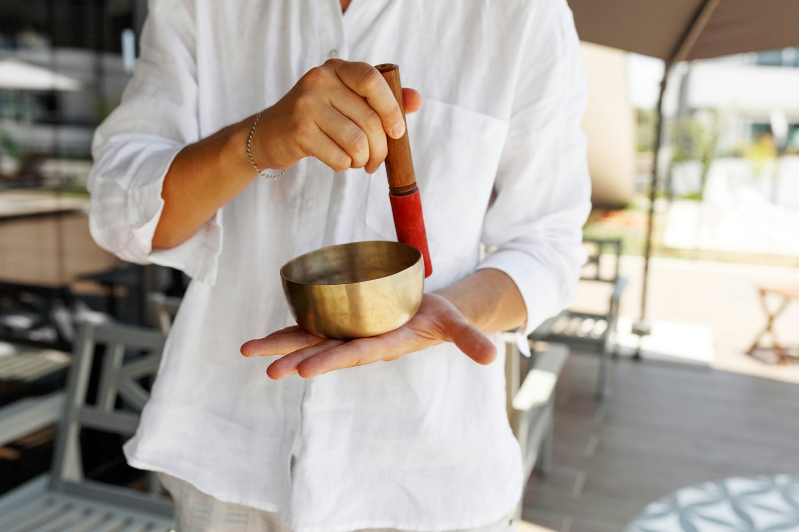 Man hands using singing bowl in sound healing therapy outdoors, closeup